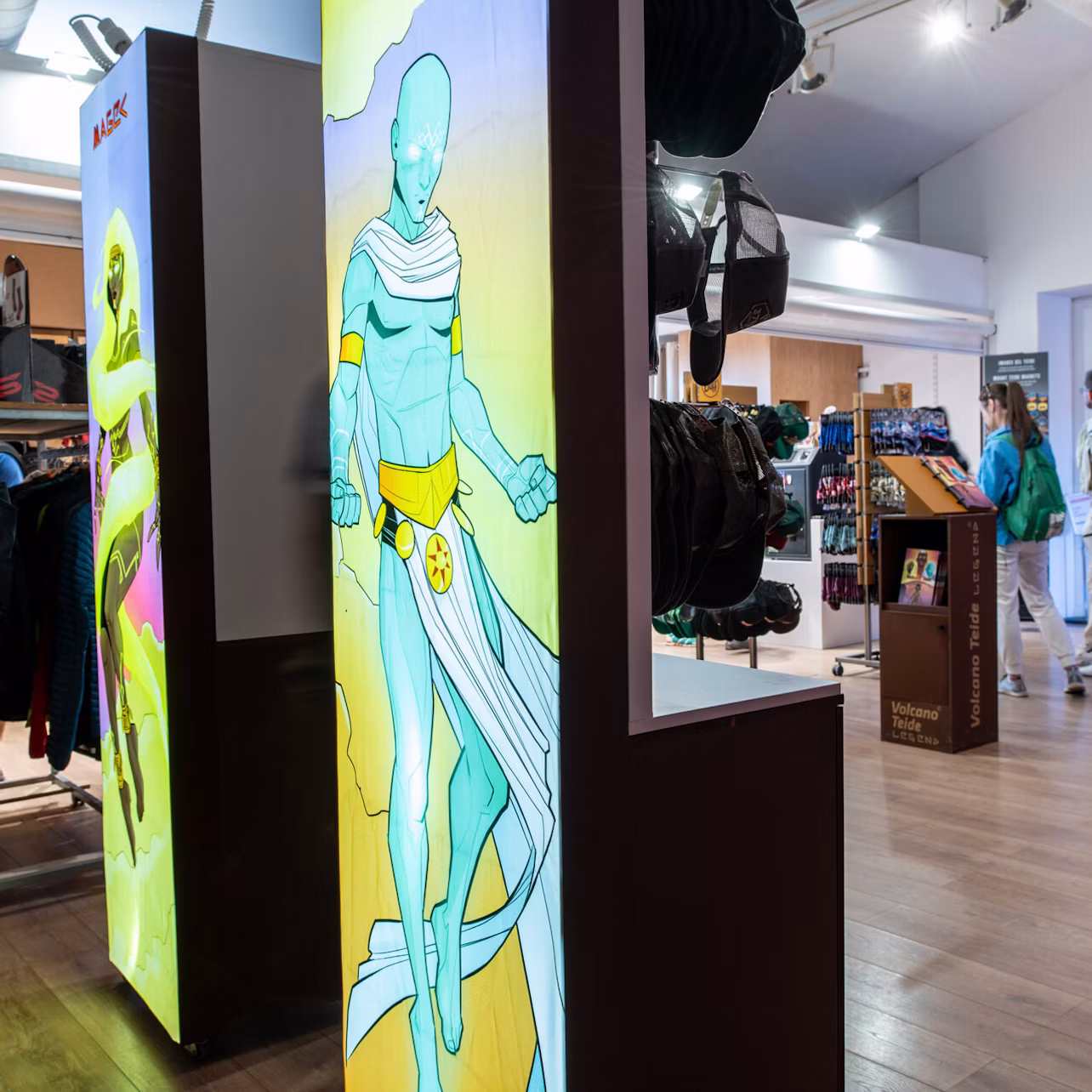 A store displaying a large poster of a blue muscular character with a white cape. Some shoppers are visible in the background.