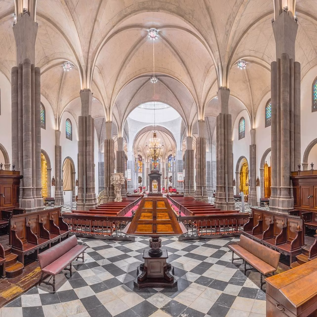 Interior of a grand church with vaulted ceilings, ornate details, and symmetrical seating arrangements.