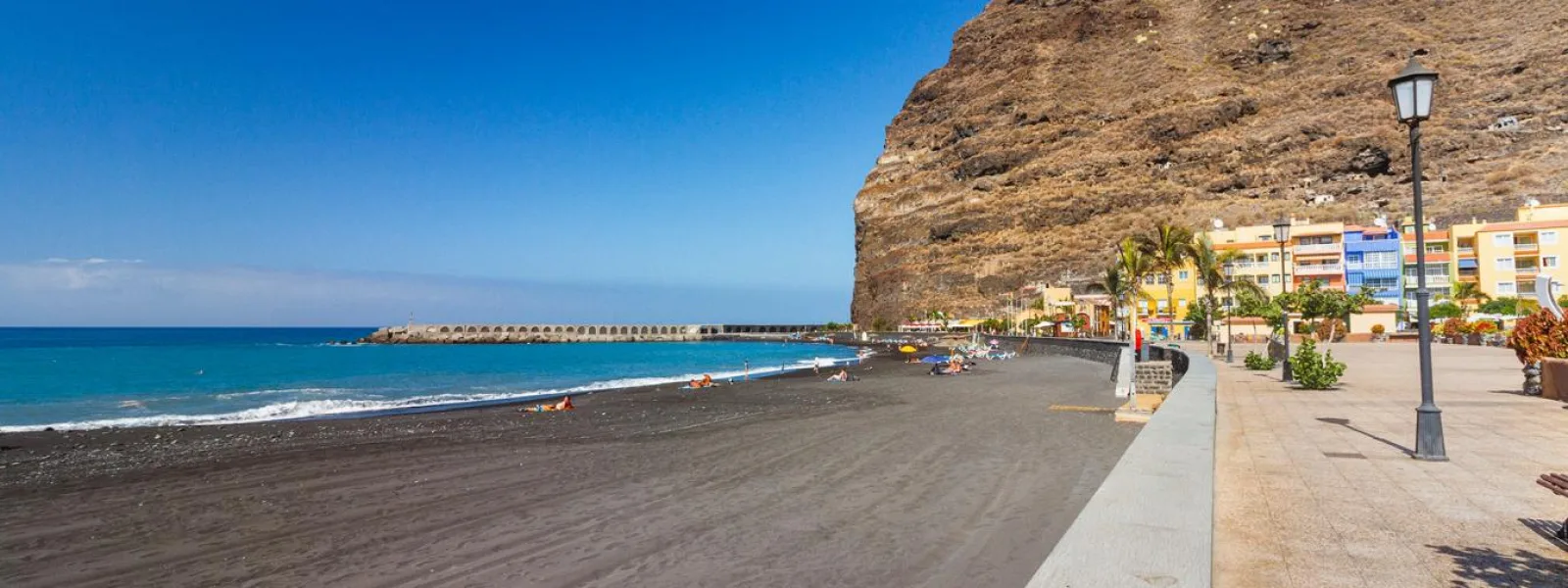 Strand op La Palma met zwart zand, promenade en vulkanische kliffen