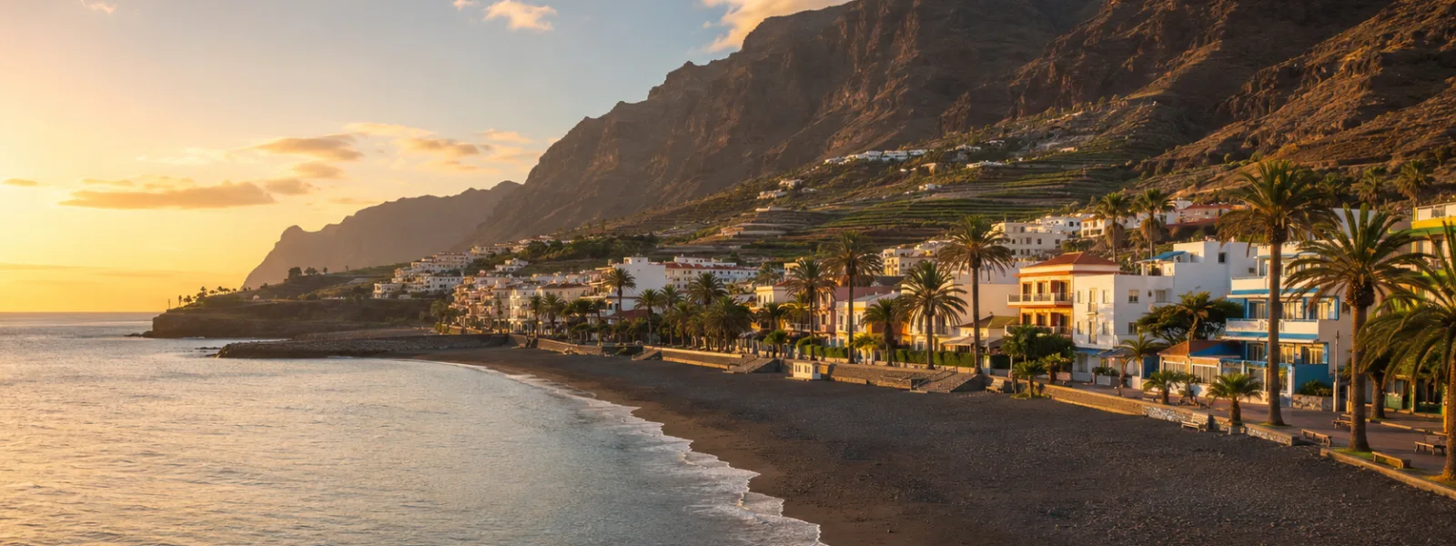 Valle Gran Rey op La Gomera met zwart zandstrand, kustappartementen, palmen en kliffen bij zonsondergang