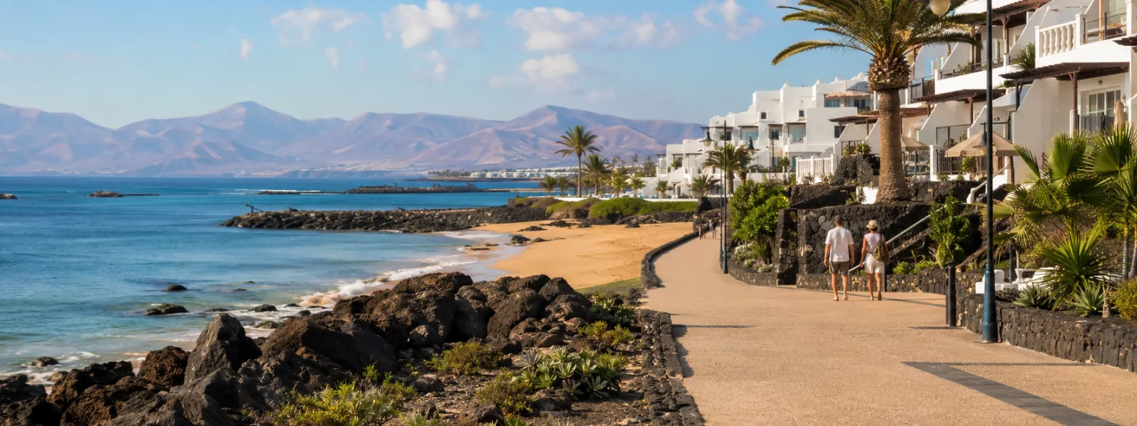 Lungomare di un resort per il sole invernale a Lanzarote con colline vulcaniche e architettura costiera bianca