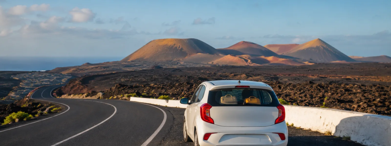 Compacte huurauto op een vulkanische weg op Lanzarote voor een reisgids over autoverhuur
