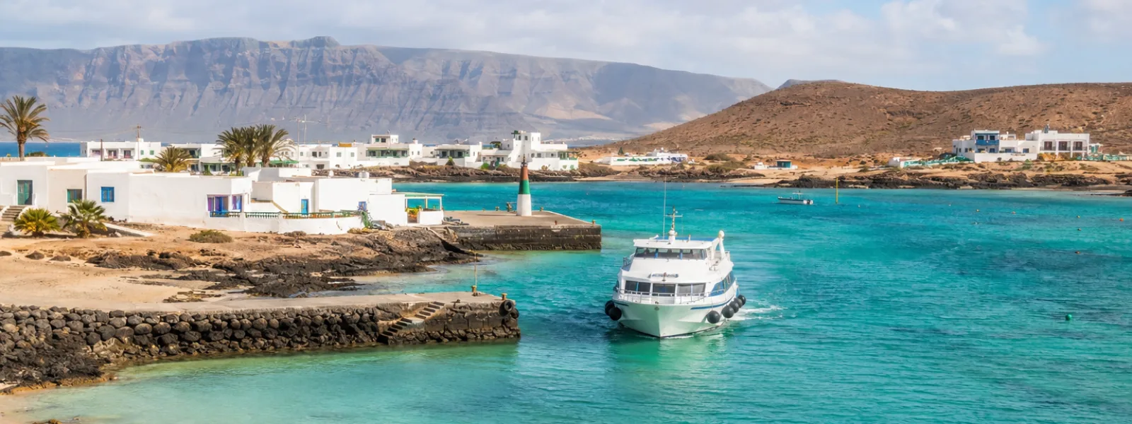 Ferry arrivant à Caleta de Sebo sur La Graciosa avec une eau turquoise et les falaises de Lanzarote