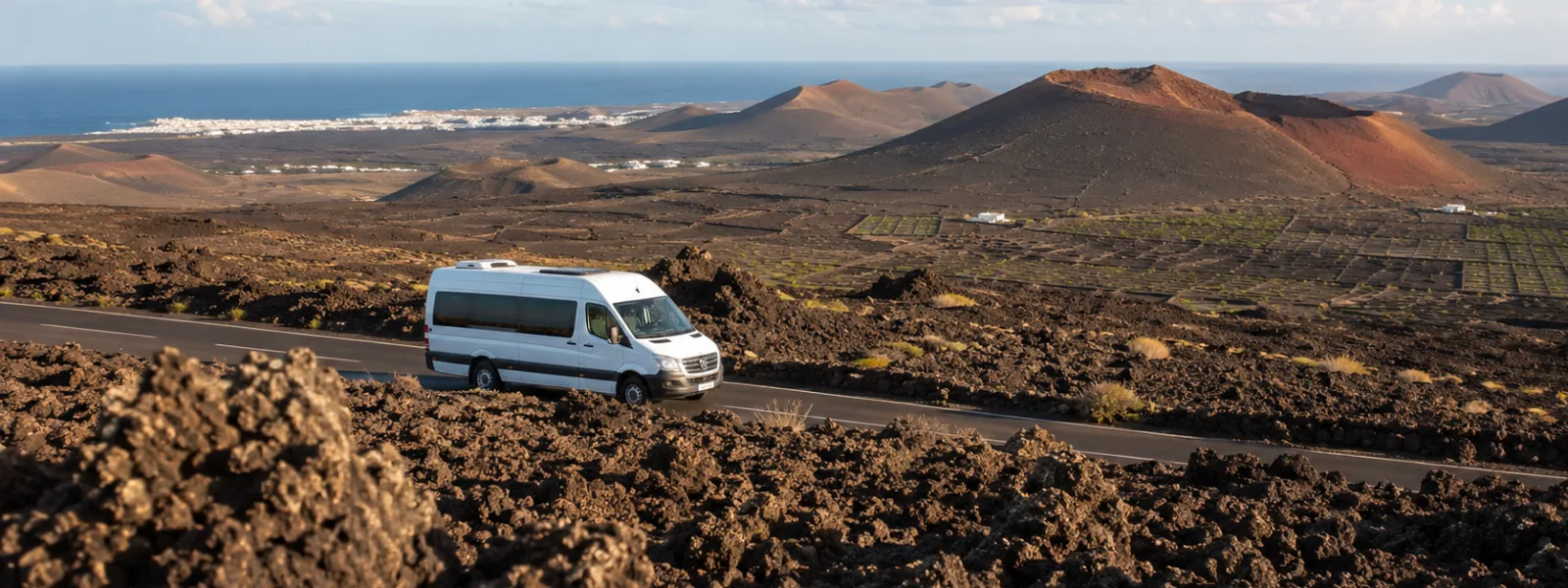 Paesaggio vulcanico di Lanzarote con un minibus turistico, che rappresenta le escursioni da Playa Blanca, Puerto del Carmen e Costa Teguise