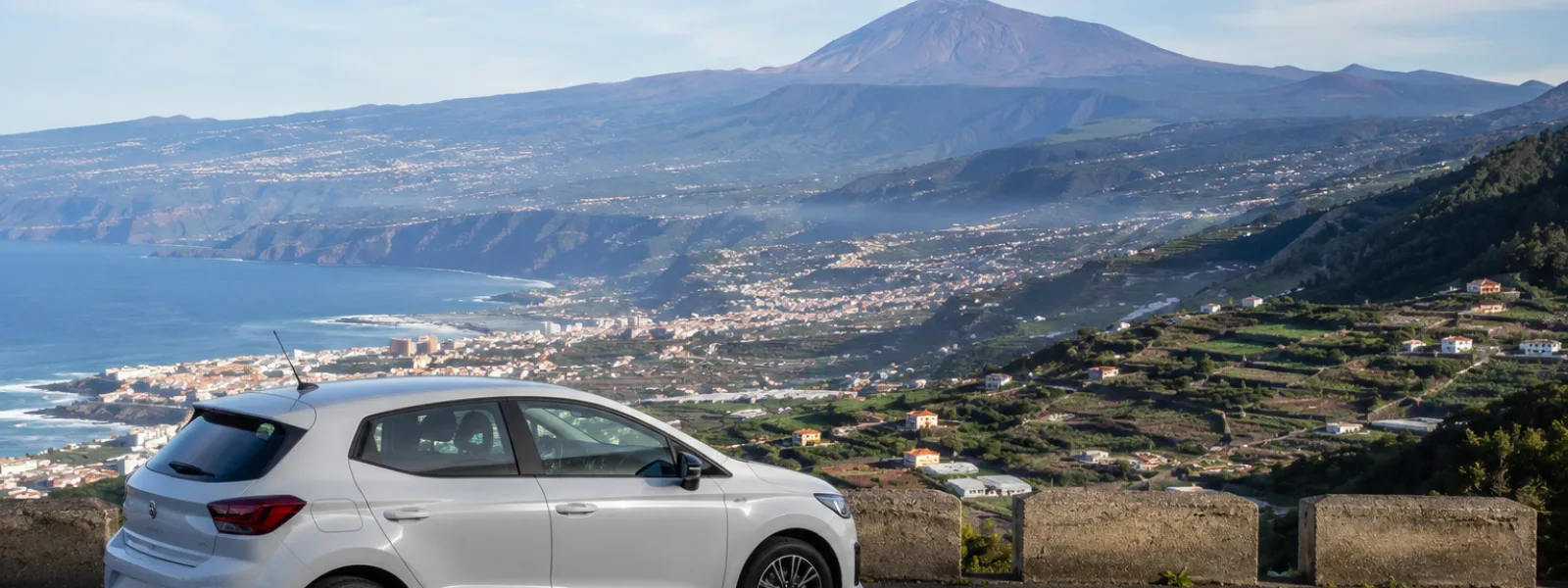 Voiture de location à un point de vue du nord de Tenerife surplombant Puerto de la Cruz avec le mont Teide au loin