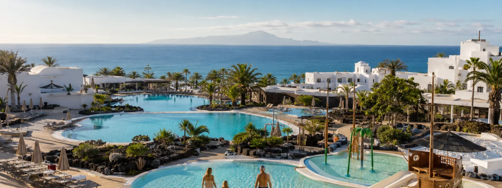 Family resort pools in Playa Blanca, Lanzarote, with a children's pirate-ship water area and the Atlantic Ocean beyond
