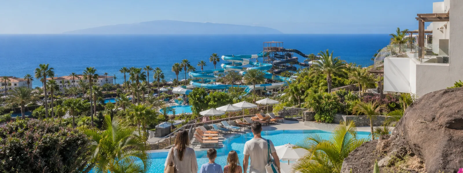 Famiglia che guarda un parco acquatico tropicale e l'Oceano Atlantico da un resort di Costa Adeje a Tenerife