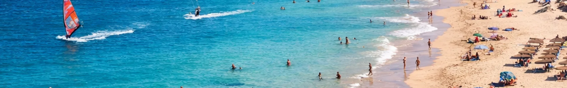 Zonnig strand op Fuerteventura met turquoise water, goudkleurig zand en vulkanisch landschap