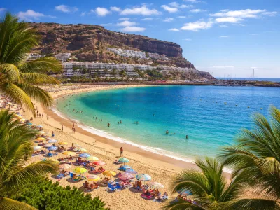 Spiaggia soleggiata a Gran Canaria con sabbia dorata, acqua turchese, palme e scogliere