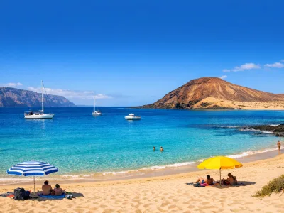 Spiaggia soleggiata a La Graciosa con acqua turchese, sabbia chiara e colline vulcaniche