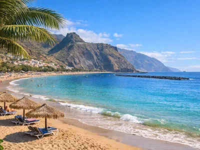 Spiaggia soleggiata a Tenerife con sabbia dorata, acqua turchese e sfondo montuoso