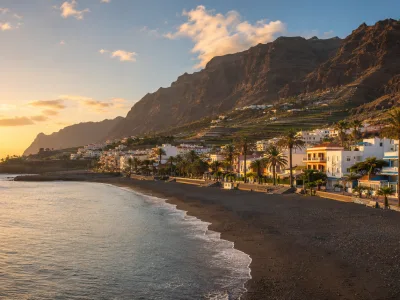 Valle Gran Rey in La Gomera with black-sand beach, coastal apartments, palms and cliffs at sunset