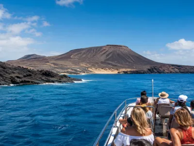 Travellers on a boat excursion approaching a volcanic Canary Islands coastline