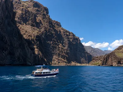 Small boat cruising below the Los Gigantes cliffs near Masca Bay in Tenerife