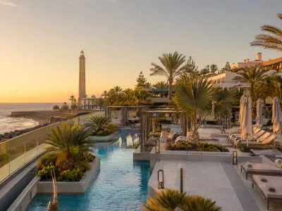 Luxury pool terraces and palm-lined Meloneras promenade near Maspalomas Lighthouse in Gran Canaria