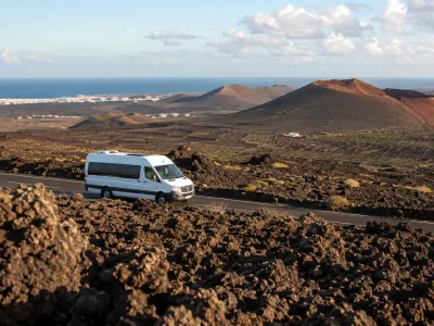 Volcanic Lanzarote landscape with a tour minibus, representing excursions from Playa Blanca, Puerto del Carmen and Costa Teguise