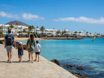 Family walking by the sheltered El Jablillo-style bay in Costa Teguise, Lanzarote