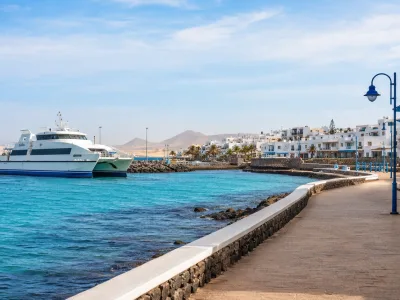 Ferry arriving in Corralejo harbour with Fuerteventura resort buildings and dunes in the distance