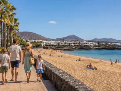 Family walking beside Playa Dorada beach and promenade in Playa Blanca, Lanzarote