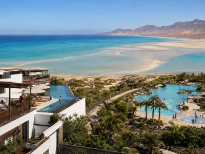 Aerial view of two contrasting beachfront resorts beside the turquoise tidal lagoon at Sotavento, Fuerteventura