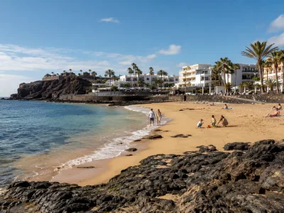 Sunny Canary Islands resort beach with volcanic rocks in November