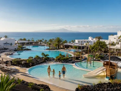 Family resort pools in Playa Blanca, Lanzarote, with a children's pirate-ship water area and the Atlantic Ocean beyond