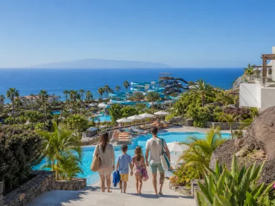 Family overlooking a tropical water park and Atlantic Ocean from a Costa Adeje resort in Tenerife