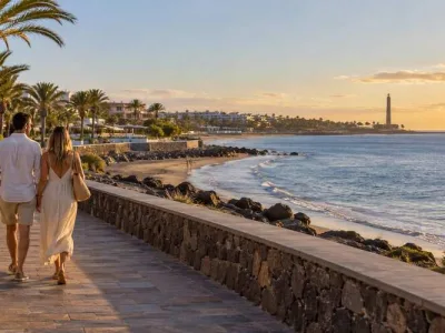 Couple walking along a quiet Gran Canaria seafront promenade at sunset near San Agustin and Meloneras