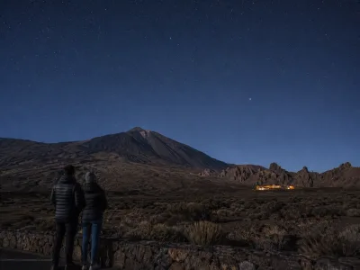 Travelers stargazing beneath Mount Teide near a mountain hotel in Tenerife