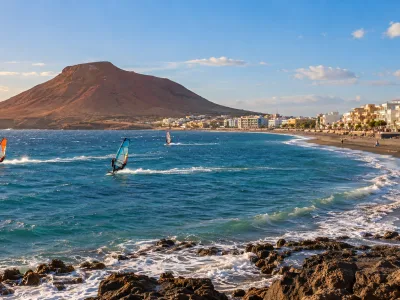 Windsurfers on El Medano beach with Montana Roja and seafront hotels in Tenerife