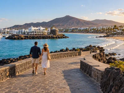 Couple walking beside a marina and golden beach on Lanzarote's volcanic coast