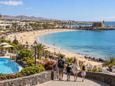 Family walking toward the sheltered beach and resort hotels of Caleta de Fuste, Fuerteventura