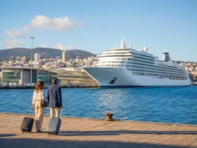 Travellers with luggage overlooking a cruise ship at the Santa Catalina cruise terminal in Las Palmas de Gran Canaria