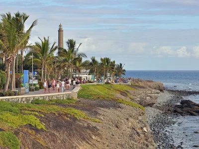 Paseo marítimo de Meloneras flanqueado por palmeras y faro de Maspalomas, sur de Gran Canaria