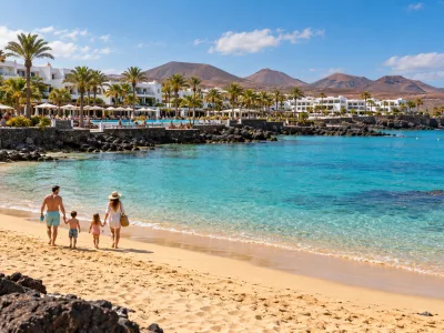 Family walking on Playa Dorada beach beside luxury resorts in Playa Blanca, Lanzarote