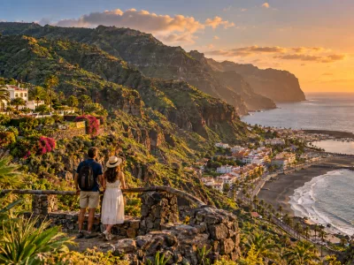 Couple overlooking La Gomera's green cliffs, black-sand coast and Atlantic at sunset