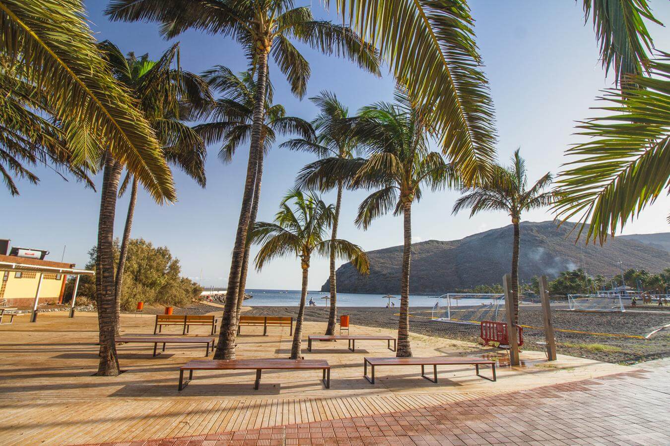 Beach in La Gomera with palm trees, calm sea and volcanic coastline