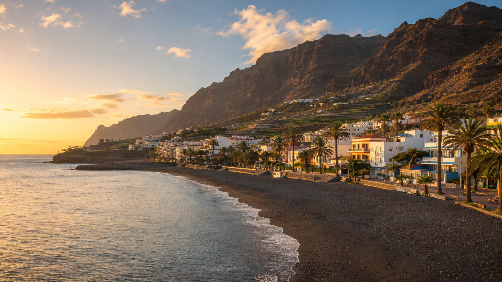 Valle Gran Rey in La Gomera with black-sand beach, coastal apartments, palms and cliffs at sunset