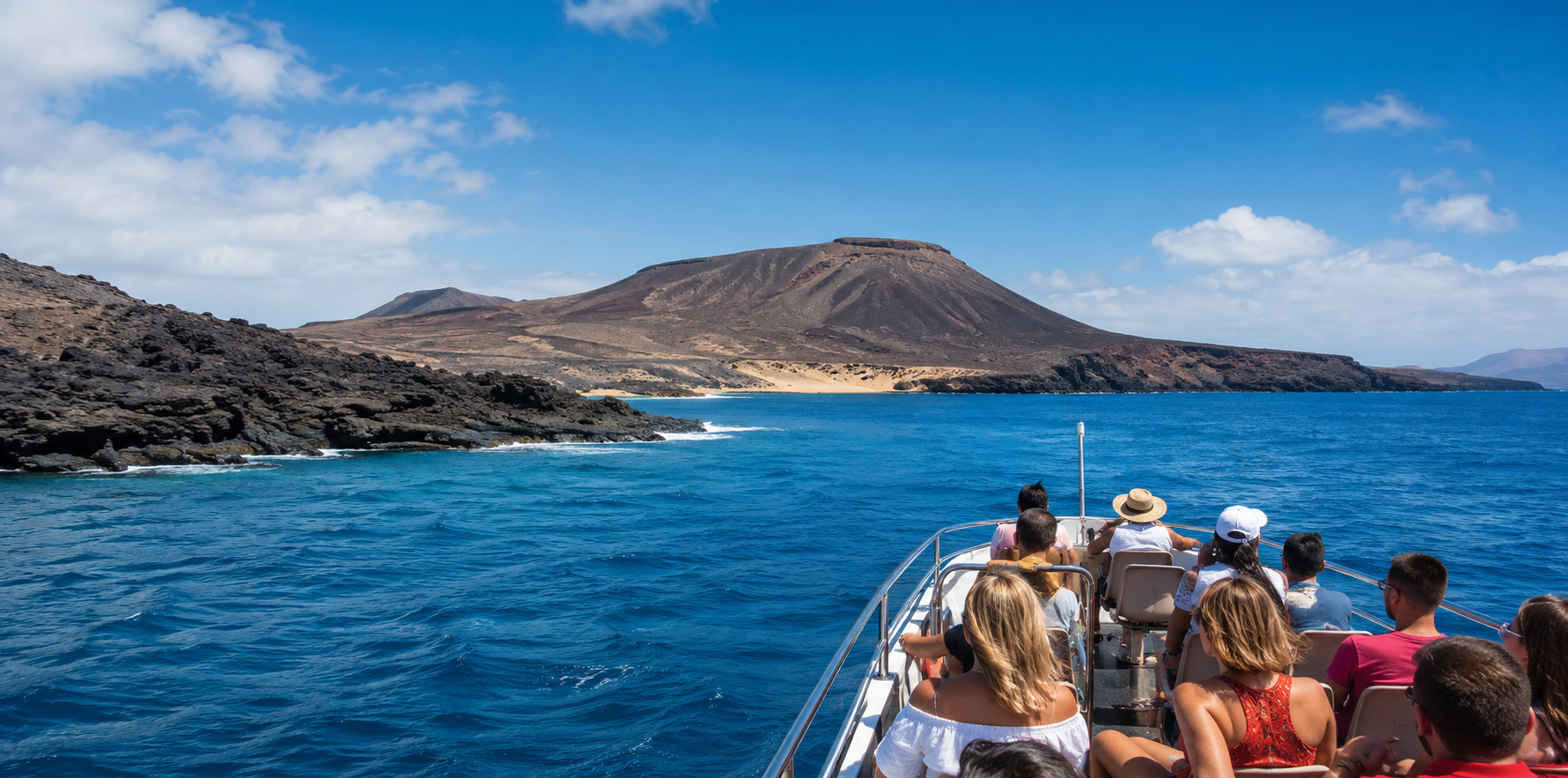 Travellers on a boat excursion approaching a volcanic Canary Islands coastline