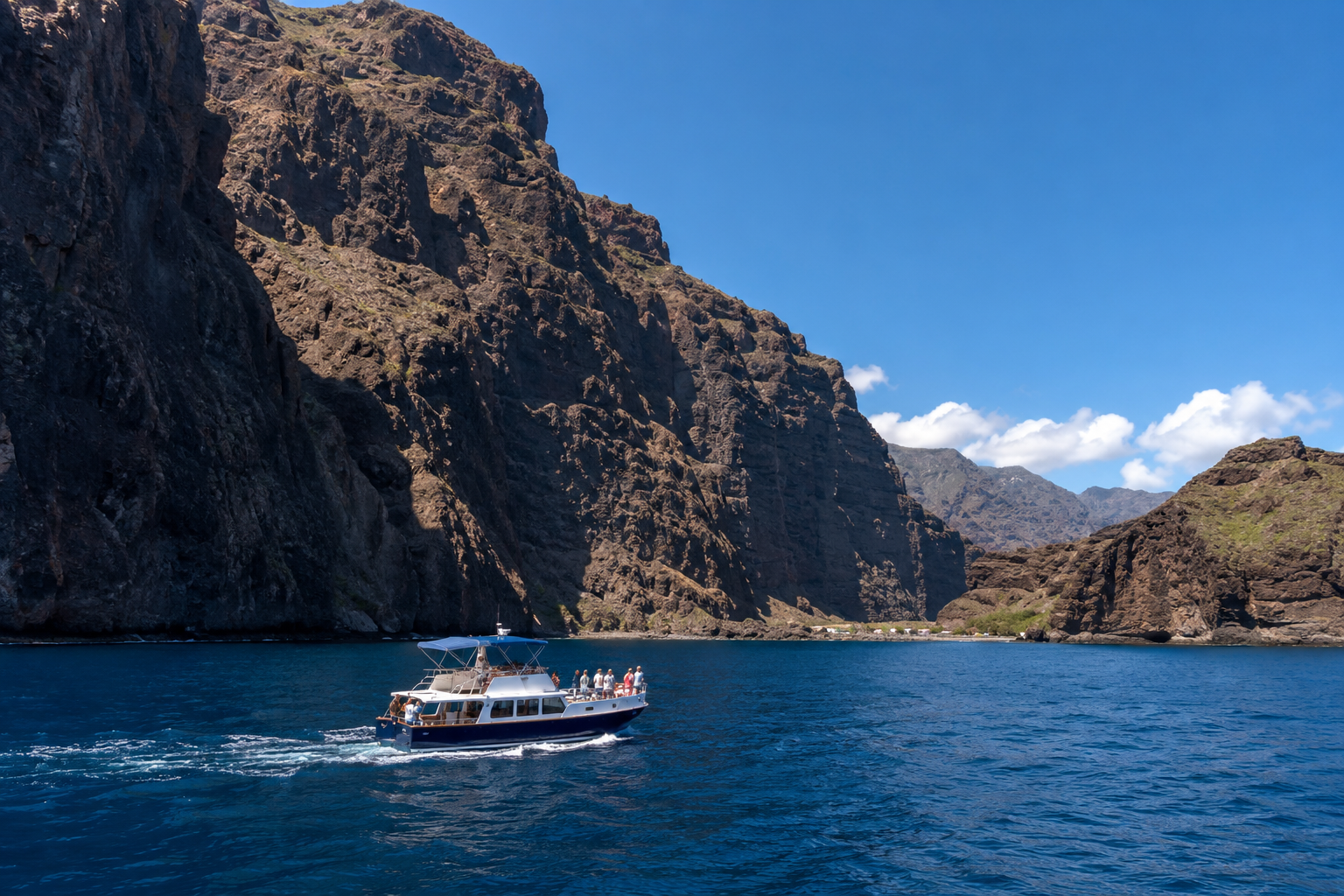 Small boat cruising below the Los Gigantes cliffs near Masca Bay in Tenerife